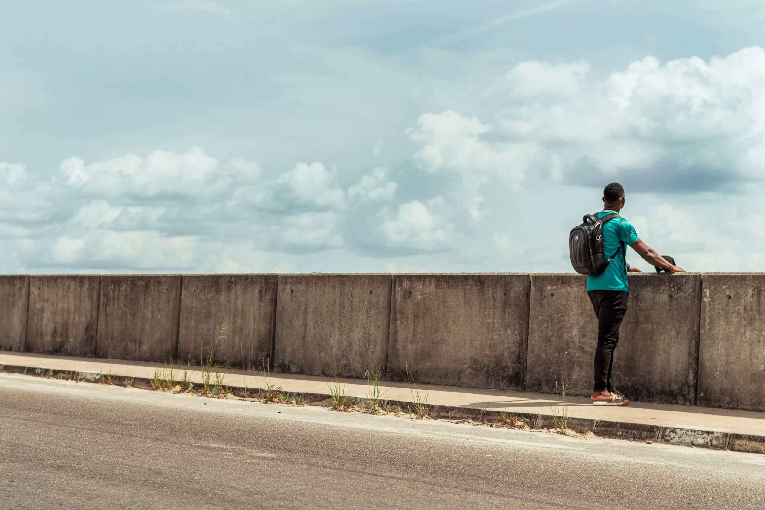 traveler on the side of a road looking over a bridge