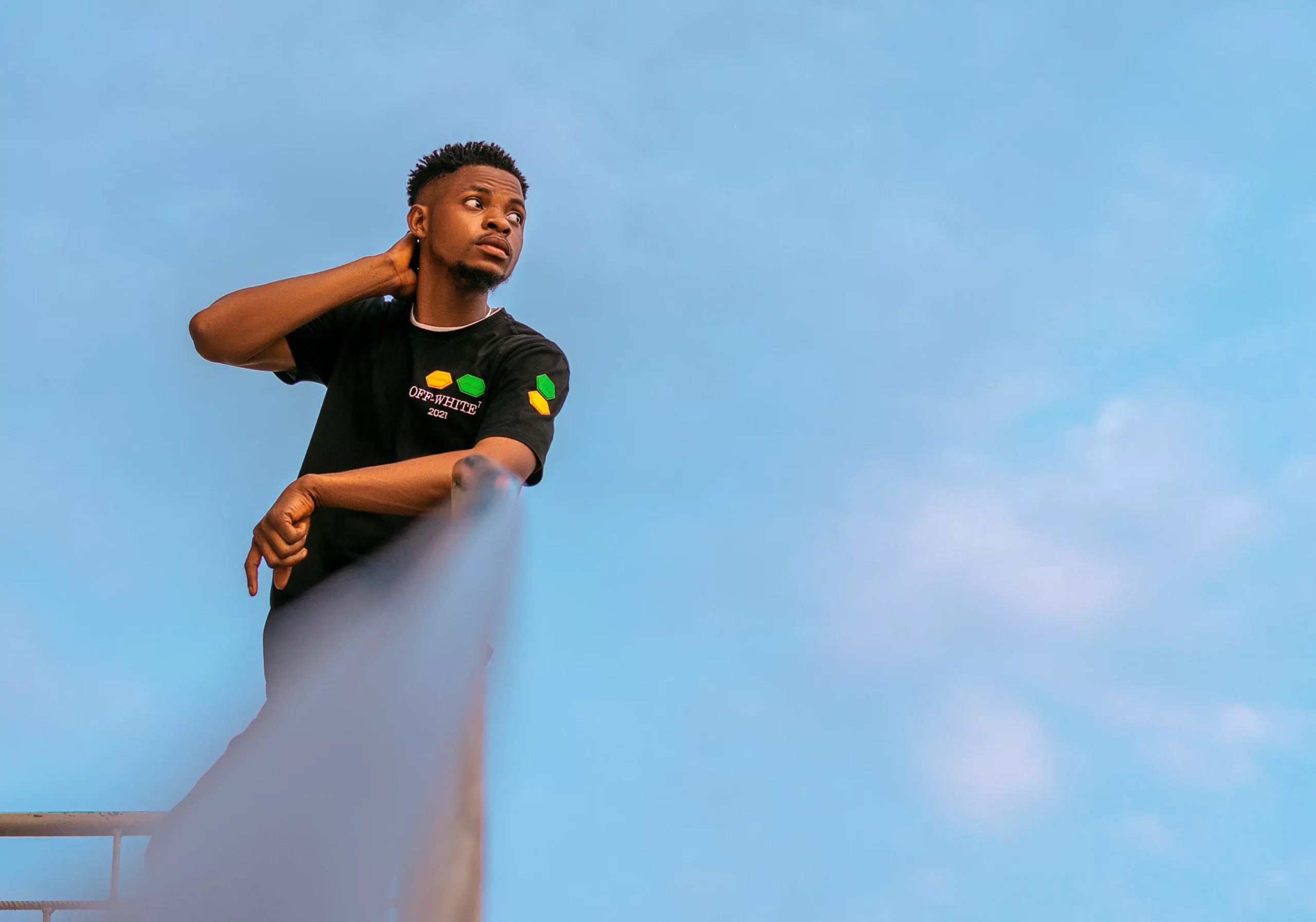 man leaning on railing with sky as background